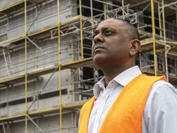 Side view of young man standing against building