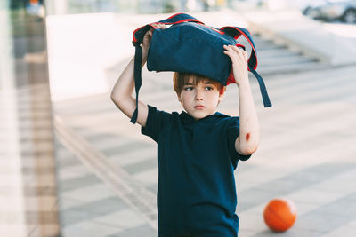 A tired boy in sports uniform and with a wound on his arm returns home after basketball training. 