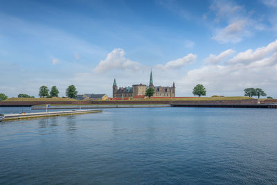 Buildings by river against sky