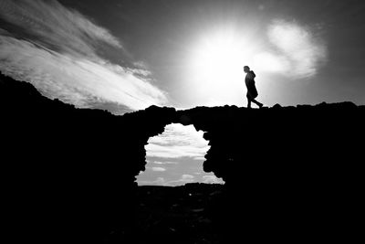 Silhouette man walking on arch against sky