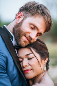 Smiling newlywed couple embracing with eyes closed