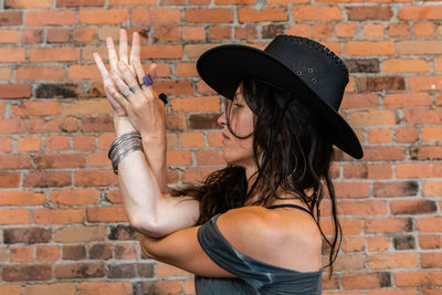 Side view of woman against brick wall