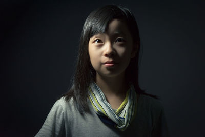 Portrait of smiling young woman against black background