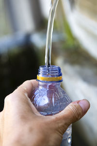 Cropped hand holding water from bottle