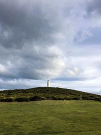 Lighthouse on field against sky