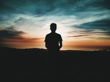 Rear view of silhouette man standing on landscape against sky