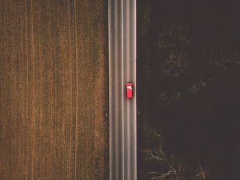 Directly above shot of red car on road amidst field