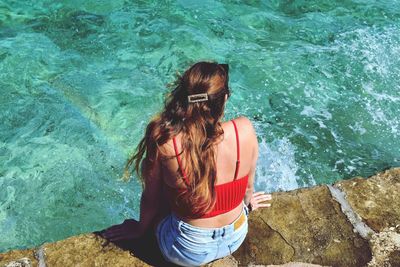 Rear view of woman sitting in swimming pool