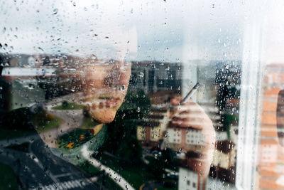 Man seen through wet glass window in rainy season