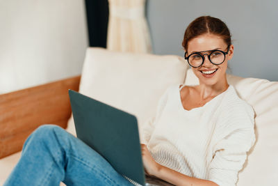 Portrait of young woman using laptop at home