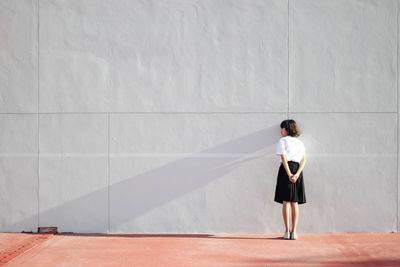 Full length of woman standing against wall