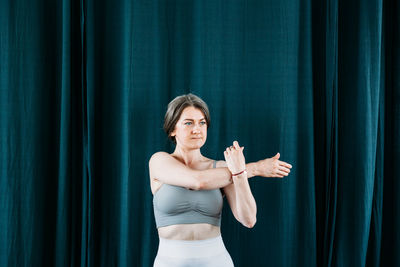 Full length of woman standing against blue curtain