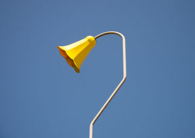 Low angle view of yellow umbrella against clear blue sky