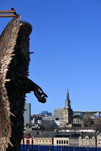 Statue of buildings in city against clear blue sky