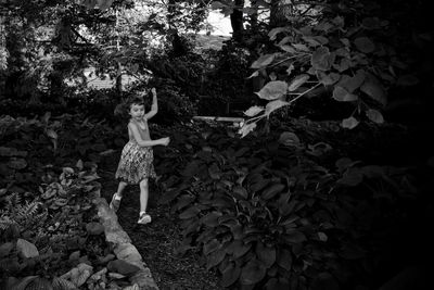 Woman standing by tree against plants