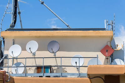 Group of round white parabolic antennas on a condominium rooftop.