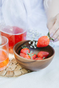 Girl holding strawberry under the wooden bowl