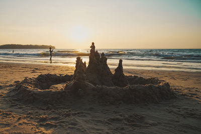 Scenic view of sandcastle at sea against sky during sunset