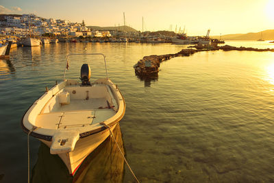 Rear view of boats moored in sea at sunset