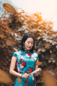 Young woman looking away while standing outdoors