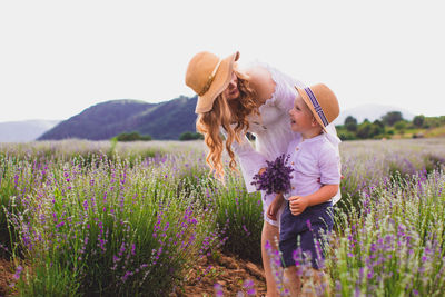 Rear view of girl with purple flowers on field