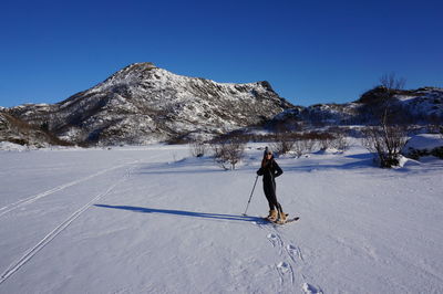 Full length of woman standing on snow covered field