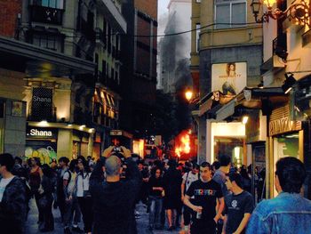 People on street amidst buildings in city at night