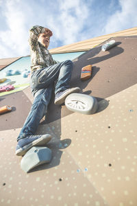 Low angle view of boy climbing on wall
