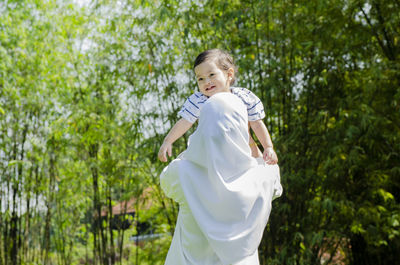 Full length of girl standing against trees