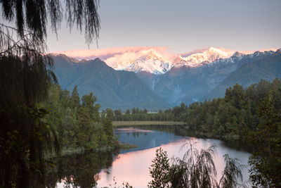 Scenic view of lake and mountains against sky at sunset