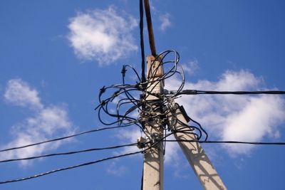 Low angle view of telephone pole against blue sky