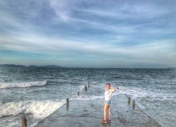 Woman standing on beach against sky