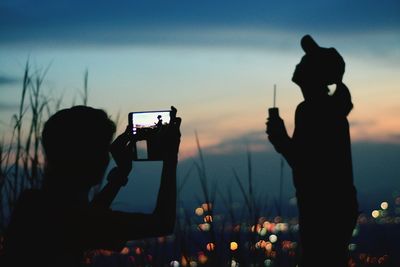 Friend photographing silhouette woman during sunset