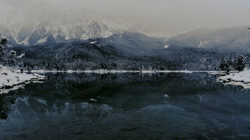 Scenic view of lake by snowcapped mountains against sky