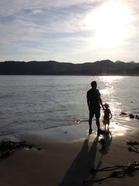 Silhouette people standing on beach against sky