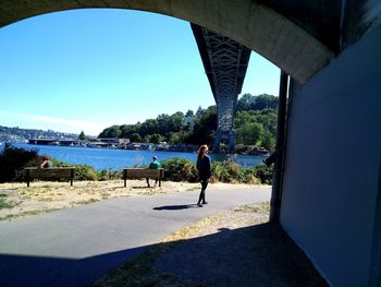 People on bridge over river against clear sky