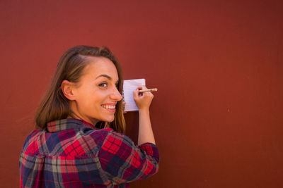 Smiling woman writing on note pad