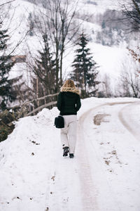 Rear view of man walking on snow covered landscape