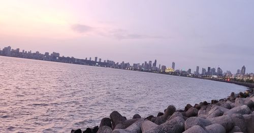 Panoramic view of sea and buildings against sky during sunset