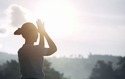 Side view of silhouette woman standing against sky