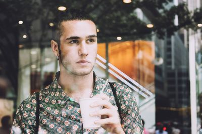 Portrait of young man drinking glass