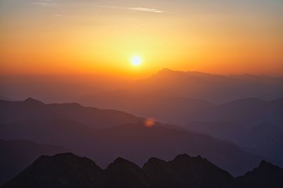Scenic view of silhouette mountains against orange sky during sunset
