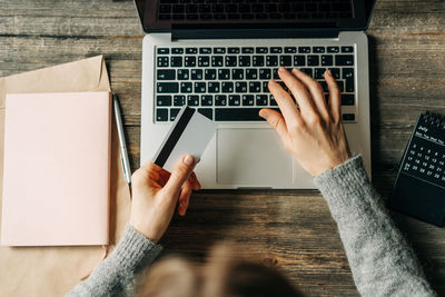 At the workplace, a woman is shopping via the internet using a bank card and a laptop.