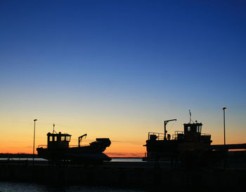 Silhouette old fishing boats dry docked against clear sky during dusk