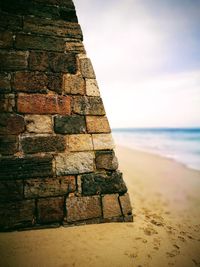 Stone wall by sea against sky