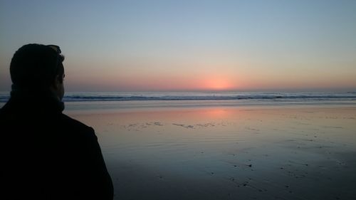 Rear view of man at beach during sunset