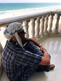 Man sitting on deck chair by sea