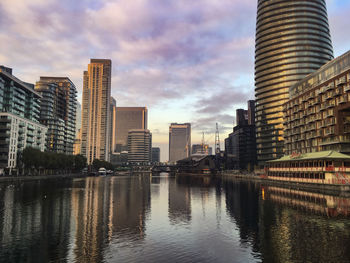 Buildings by river against sky in city