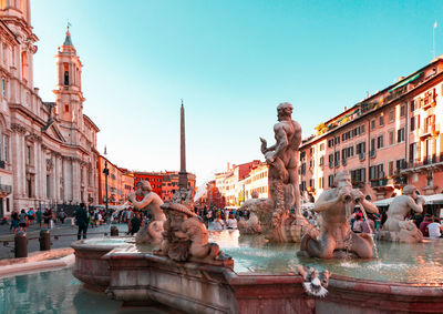 Statues in fountain amidst buildings in city