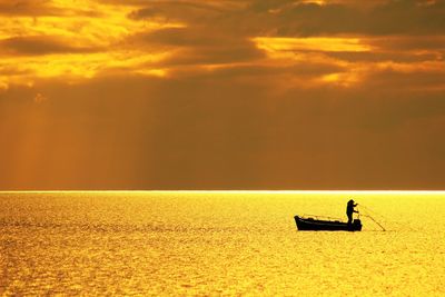 Silhouette people on sea against sky during sunset